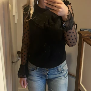 Svart blus - jättefin ”blus” från kappahl med fina volanger i ärmarna. Jättefint skick och säljer då den sitter lite tajt.
