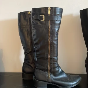 Stövlar - Säljer dessa fina svarta stövlar med guld detaljer. Dom är så sköna och perfekt till höst och vinter då dom är varma där i ( sista bilden ). Sköna att gå i då dom har låg klack!!  Jätte fint skick!! Står att de är storlek 41 men skulle säga 40 