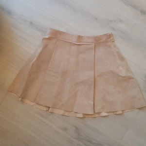 Retro skinn kjol HM stl 38 - Mocka/skinn kjol från HM Veckad utsvängd  Dragkedja i sidan Supersnygg! Inget att anmärka på.