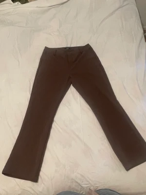 Bruna utsvängda kostymbyxor  - Bikbok bruna utsvängda byxor. Storlek 48 och passar perfekt för långa ben, är själv 172.   Använd bara engång. De va för stora. Original pris 499kr