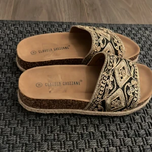 Tofflor - Jättesnygga tofflor som är bruna med svarta och guldiga detaljer. Knappt använda. Storlek 36. 150kr + frakt