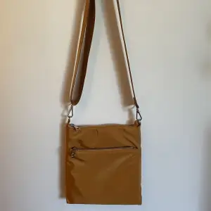 Liten orange/brun väska från Lindex. Använd men i fint skick. Justerbart axelband. 