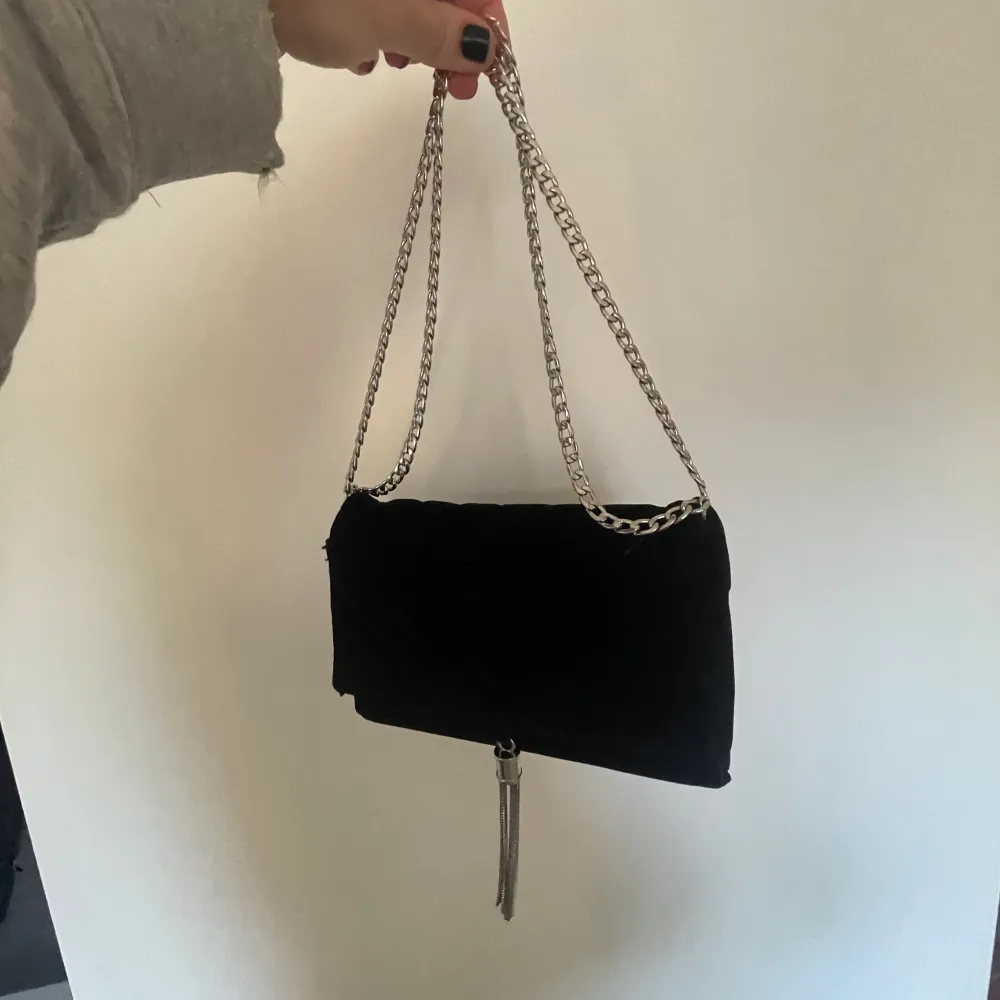 Säljer en liten svart väska i sammet med silver detaljer. Dock såpass stor att man får ner telefon, nycklar etc💕. Väskor.