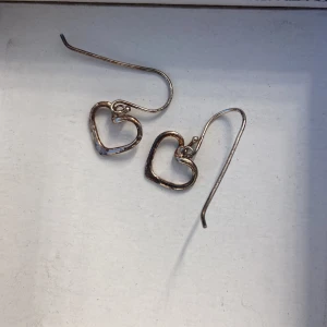 Hjärt örhängen  - Säljer dessa silvriga örhängena då dom inte används länge. Lite osäker på material. Osäker om det är rost som kan gå bort eller om det är missfärgning. KÖPAREN STÅR FÖR FRAKT 