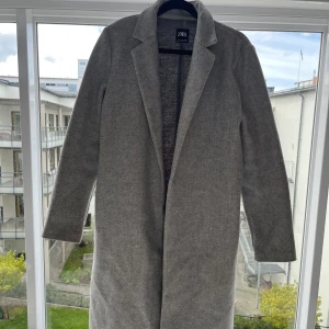 Kappa  - Grå lång kappa. Går strax nedanför vaden på mig som är 158