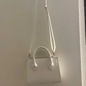 Väska - Vit crossbodybag med avtagbara band. 