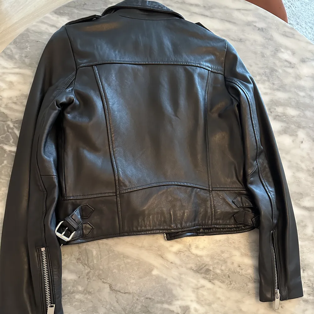 ZARA WOMAN COLLECTION  Bikerjacka i 100 % skinn.  Långärmad. Öppningar i ärmsluten. Framfickor. Knäppning fram med metalldragkedja. Nypris: 2500 Stl: S ( normal i stl ) regularfit  Har använt Max 2 ggr, helt ny Svart! (Liknar Acne jackan ). Jackor.