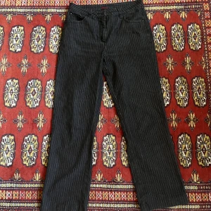 Svarta jeans - Ett par mid rise svarta jeans med vita ränder Midjemått: ca 74cm Innerbenslängd: ca 71cm (sitter lagom på mig som är ca 162)