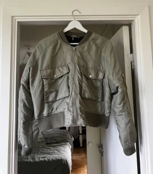 Grön bomberjacka  - En fin grön bomberjacka i storlek L ifrån H&M. Bomberjackans modell är lite kortare och är oversized. Jackan är endast använd ett par gånger och är i bra skick med inga skador eller liknande ❤️  100% polyester 