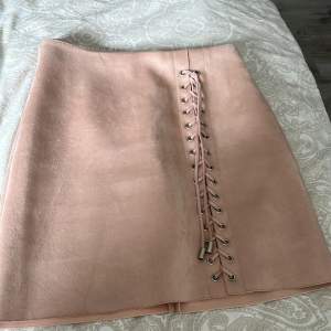 Rosa kjol i mocka imitation med jättefin snörning. Tråden har släppt ungefär 2 cm i bak men går lätt att fixa med nål och tråd (bild 2)