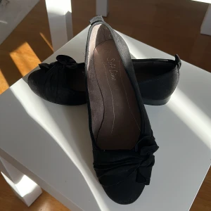 Svarta ballerinaskor  - Ett par jättefina svarta ballerinaskor som jag knappt har använt i storlek 37 med söt knytdetalj