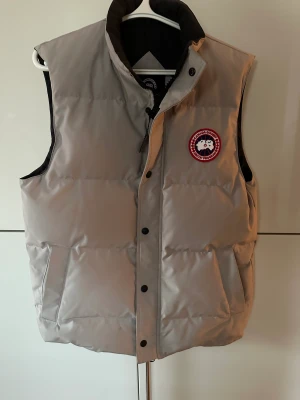 Äkta Canada Goose väst - Säljer en vit/beige canada goose väst. Använd fåtal gånger. Nypris 5999