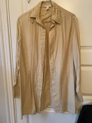 Beige skjorta, lite glansig, lite längre modell 