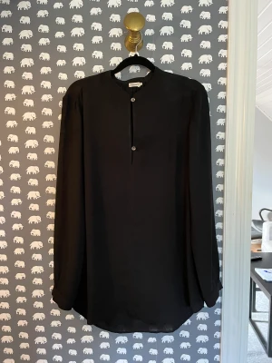 Filippa K blus  - Svart tunn blus i en längre modell från Filippa K. Str 38. Fint skick.