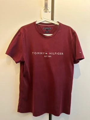 Vinröd Tommy Hilfiger M-L - Detta är en vinröd Tommy hilfiger, som är i väldigt gott skick. Är i storlek M-L
