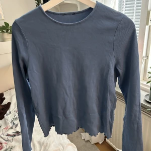 Blå långärmad topp  - Köpt second hand och kommer aldrig till användning. Märks dock att den har använts och tvättats av den förra ägaren då tyget är lite stelt. Vet ej vilken storlek eller märke då alla lappar är avklippta, men som referens brukar jag har storlek M. 