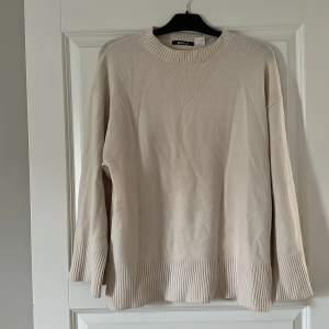 En finstickad beige tröja från Gina tricot med vida ärmar.