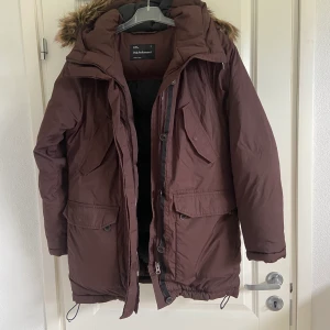 Peak Performance Vinterjacka - En varm och skön vinterjacka från Peak Performance i en brun/vinrödfärg. Värmer bra och har mycket fickor. Storlek L