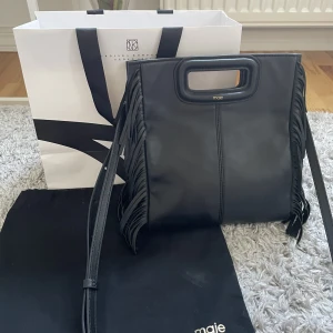 Maje M Bag stor svart - Intressekoll på min Maje väska i svart, stora storleken! Väldigt fint skick förutom lite sliten på baksidan av handtaget och en liten repa på väskan som inte syns utom på nära håll (kan skicka bild!) Dustbag och långt band ingår💕 Nypris 2999 kr🫶🏻 