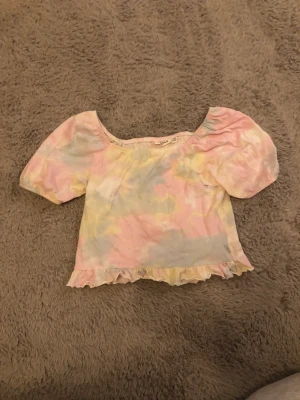 Topp - En pastellfärgad topp med en fin worlang längst ner och ribbad i ryggen