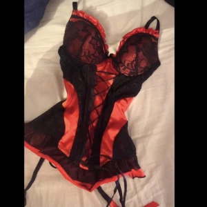 Korsett sexig topp med smala axelband röd, rosett goth - En korsett, typ topp med smala axelband, med kupa och Ljusterbart i ryggen. Röd/vinröd färg, men svarta dekorationer  Kupa C ungefär  Storlek S/M Sexiga hängslen som fästes vid strumpor och sådant. Aldrig använt, helt ny och fin ❤️