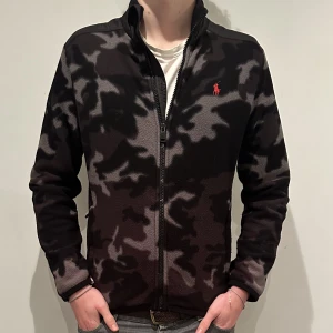 Ralph Lauren camoflage fullzip - Snygg Ralph Lauren fullzip i grymt skick, inga defekter. Den är i ett tunnare fleecmaterial. Storlek L (Barn) men sitter som en Xs. Modellen är 180 cm. (Han bär oftast S, denna är lite liten). Säljer för 599. Skriv vid minsta intresse!