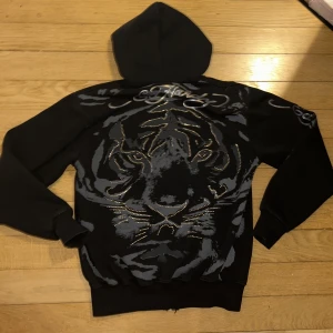 Edhardy hoodie zip-hoodie - En cool edhardy hoodie med rhinestones i super bra skick!💗En likadan hoodie såldes för 1200kr men säljer för lite billigare🙌 Passae både killar och tjejer