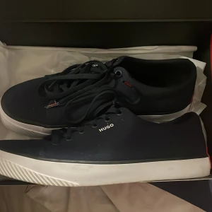 Marinblå Hugos boss skor  - Ett par fina Hugos boss skor till herr.Använda en gång ,lite smuts nere vid de vita på sulan.säljes då de är förstora.