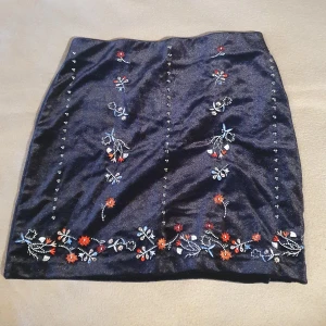 Oanvänd Sammetskjol med broderier och stenar - Svart sammetskjol med blommiga broderier och stenar. Stretchigt material och midjeband 🖤 helt oanvänd med lapp kvar 