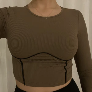 Ribbad topp  - Ribbad topp i mockabrun med svarta detaljer Aldrig använd