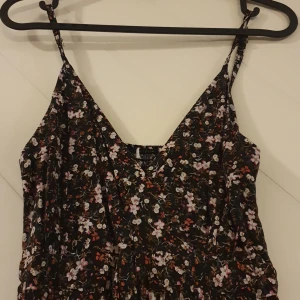 Blommig klänning  - Blommig klänning.   100% viscose.  Draperad i ryggen.  Tunna axelband. 