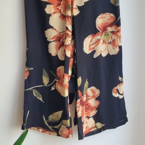 Somrig mönstrad julpsuit - Jumpsuit från Shein i härligt mönster. Halterneck knytning i nacken och låg rygg. Aldrig använd. Stl S. 50 kr rabatt vid upphämtning. 