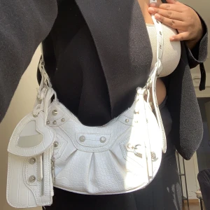 Axel/crossbodybag - Väskan har en spegel och en liten korthållare som detalj. Går även att justera så att man kan bära den som axelremsväska och crossbody.   Obs! Spegeln är tyvärr sönder men går enkelt att ta bort och byta ut, lite missfärgningar men inget märkvärdigt.