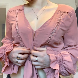 Rosa blus - Rosa luftig blus, det är knappar på framsidan sen knyter man i ärmarna och vid midjan