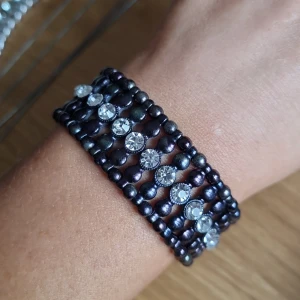 Elastiskt pärlarmband  - Elastiskt pärlamband med strass  Färgen är lite mörkt lila metallic 
