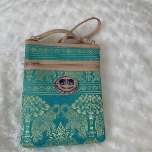 Mobilväska - Vacker mobilväska i perfekt skick! 🤩💚💙Köpt i Thailand och är helt ny och oanvänd.  Mått: Bred 16 cm Höjd 20 cm Axelband 113 cm  Väger ca 200 g