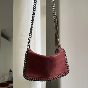 Stella liknande väska - Vinröd stella mccartney liknande väska i äkta skinn och väldigt bra kvalitet. Tyvärr lite missfärgad på skinnet och kedjan men märks ej så mycket när man har den på sig