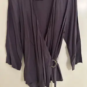 Wrap blouse med 3/4 lång ärm. Från Stockh lm. Färg lila, storlek M.Viss oxidering på metallen. 