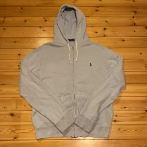 Polo Ralph lauren zip hoodie  - En mycket fin polo Ralph lauren zip hoodie. Den har ett litet hål på baksidan vid luvan men det syns inte när du har på dig den då luvan täcker det. Storlek L men passar bra till M. Nypris 2200