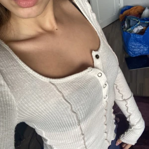 Vit långärmad  - Snygg vit långärmad tröja men knappar vid bröstet. Köpt på Urban Outfitters och är endast använd 2-3 gånger. 