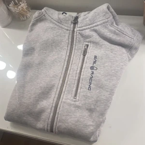 Sailracing hoodie - Säljer mina gråa sailracing hoodie då den inte används längre. Den köptes förra året och den är knappt använd och i nyskick. Nypriset är runt 1000-1500kr