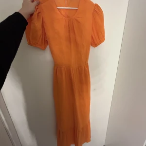 Orange maxiklänning med puffärm - Köpt för nåt år sen men har aldrig kommit till användning! Köpt för 599 kr.