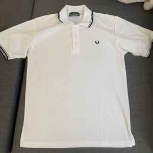 Piké t-shirt - Knappt använd fred perry piké t-shirt som passar till mycket. Storleken är lite stor men passar på folk i storlek M.  Jag står för tvätt och strykning innan den levereras.
