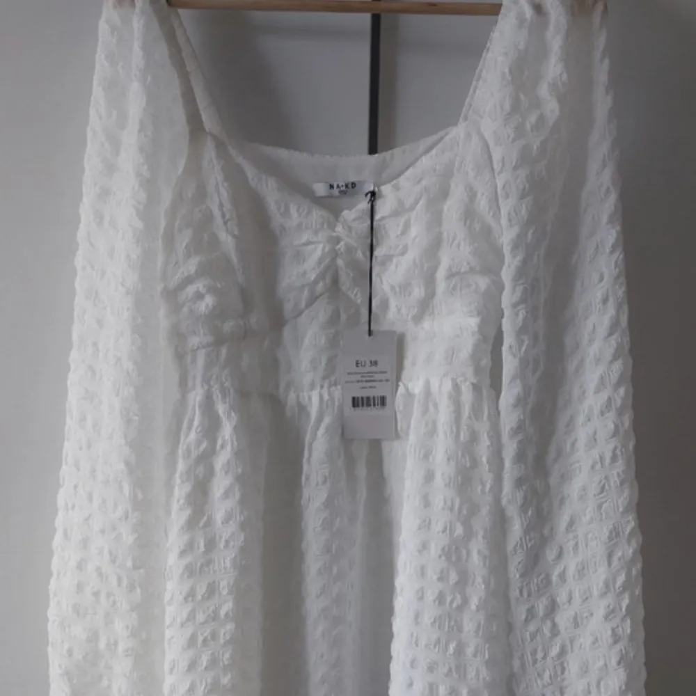 Säljer en oanvänd vit klänning från nakd i storlek M . Klänningar.