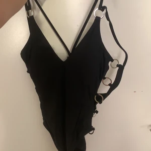 Baddräkt  - Oanvänd baddräkt, öppen på sidorna med ringar längst med. Aldrig använd endast testad. 