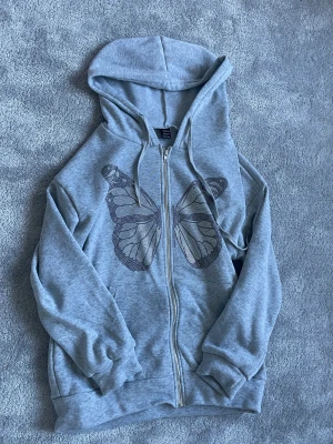 Grå hoodie med tryck  - Jag säljer min fina gråa zip hoddie med fjärlistryck eftersom den inte kommit till användning. I storlek Small. Nyskick!!🥰