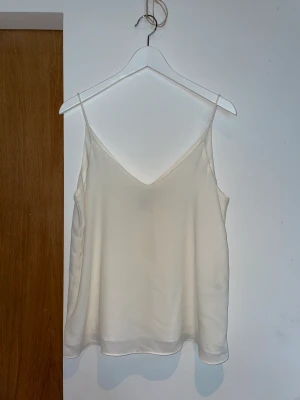 Vitt linne - Vitt luftigt linne. Smala axelband.  Klockad figur