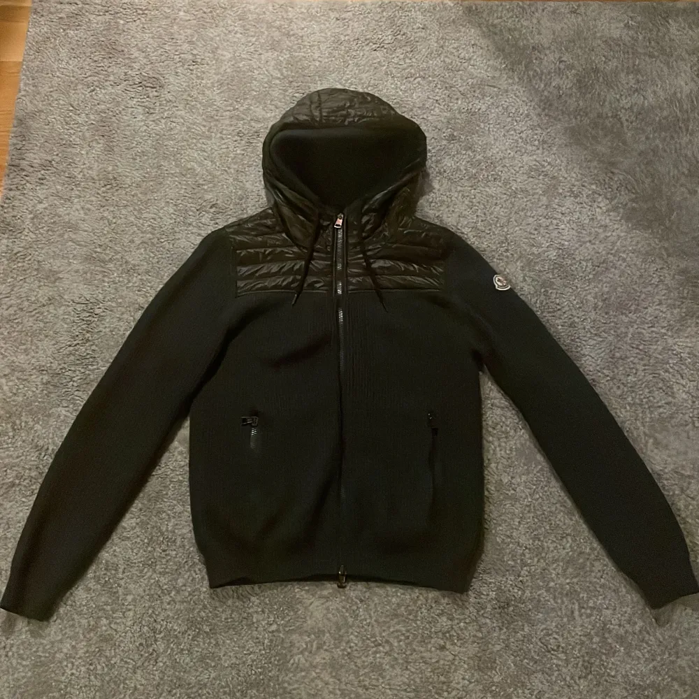 Säljer Moncler Hybrid Cardigan! Säljer pga inte använder längre. Köpt tidigare av Garmsmarket. En liten skada vid sömmen längst ner på cardiganen som fanns när den tidigare köptes, ihopsytt. Inget jag märkt av när jag använder den. Grå/grön storlek M. Tröjor & Koftor.