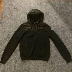 Moncler hybrid cardigan - Säljer Moncler Hybrid Cardigan! Säljer pga inte använder längre. Köpt tidigare av Garmsmarket. En liten skada vid sömmen längst ner på cardiganen som fanns när den tidigare köptes, ihopsytt. Inget jag märkt av när jag använder den. Grå/grön storlek M