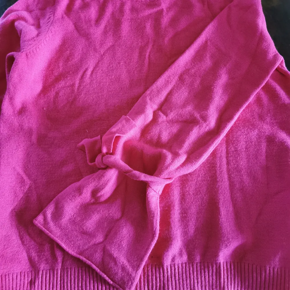 Fin rosa tröja med knytdetaljer på ärmarna från NA-KD. Storlek xs och fin i skicket. Finns katter i hemmet så kan finnas lite katthår på kläderna. Bredd: 43 cm, längd: 53 cm. Är som färgen på de första två bilderna, sista bilden är för att visa ärmarn. . Stickat.